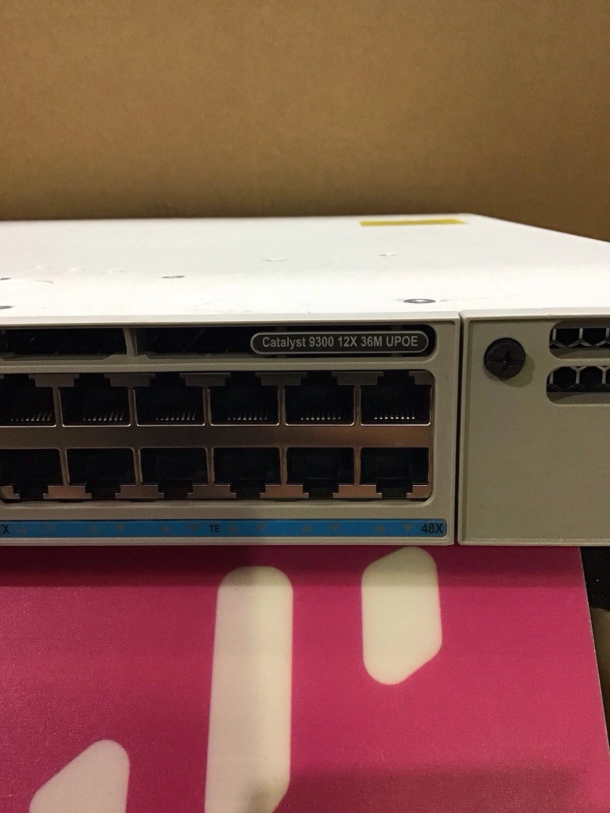 White cisco catalyst 9300 series network switch with black ethernet ports and blue indicator strip for multi gig connectivity